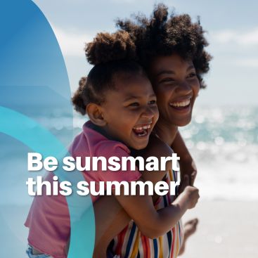 Smiling mother carrying her child at the beach with text promoting sunsmart summer habits.